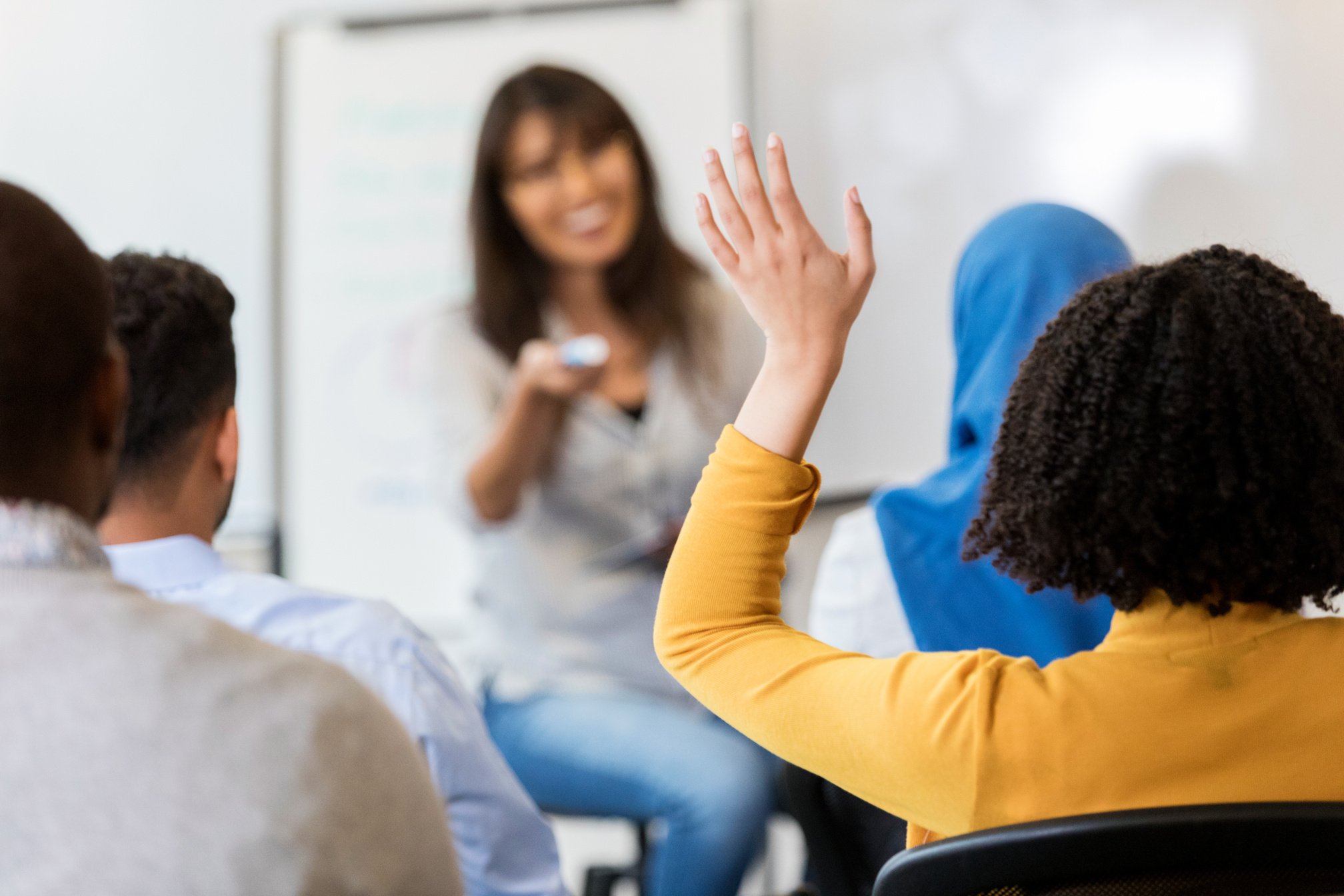 Unrecognizable adult student raises hand in class